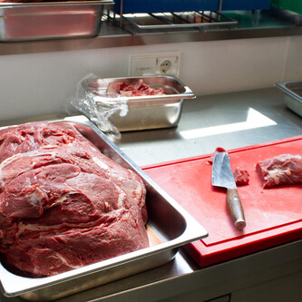 Haufen Fleisch neben Messer auf rotem Schneidbrett | © Land schafft Leben