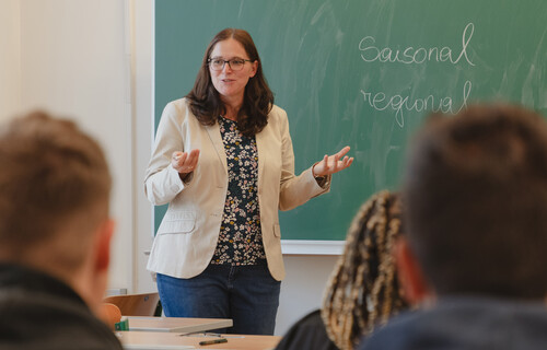 Lehrerin steht vor Tafel in Schule | © Land schafft Leben