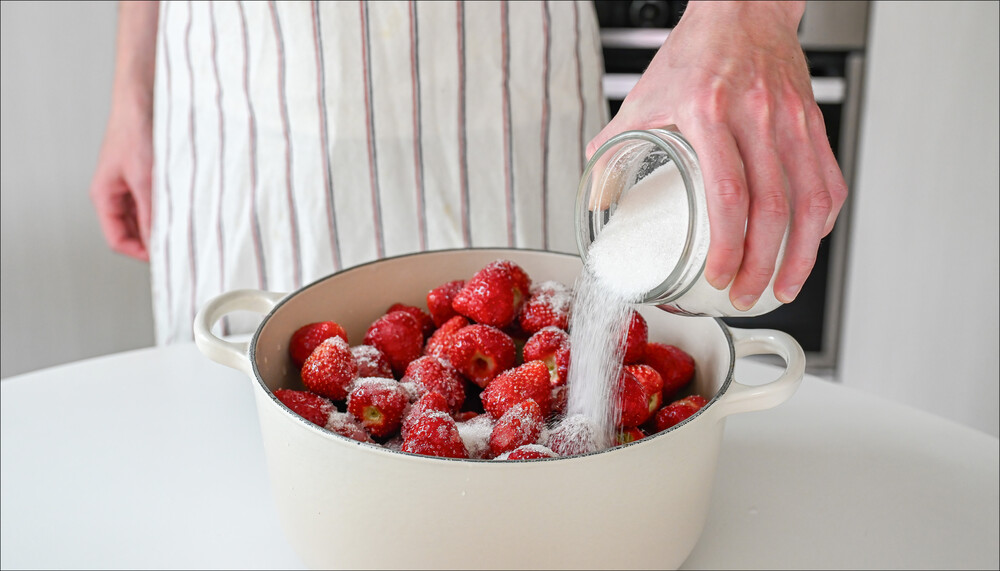 Für die Herstellung von Erdbeerkonfitüre, Gelee oder Marmelade werden werden in einem weißen Topf Erdbeeren mit Gelierzucker überstreut. | © Freepik