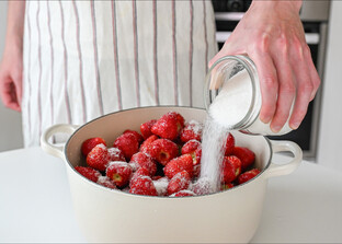 Für die Herstellung von Erdbeerkonfitüre, Gelee oder Marmelade werden werden in einem weißen Topf Erdbeeren mit Gelierzucker überstreut. | © Freepik