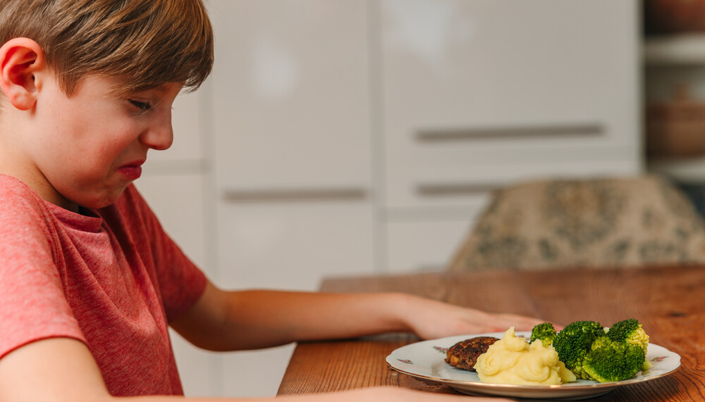 Kind mit Teller Brokkoli und Kartoffelpüree verzieht das Gesicht | © Land schafft Leben