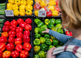 Eine Frau greift nach einem grünen Paprika im Supermarkt. | © Land schafft Leben