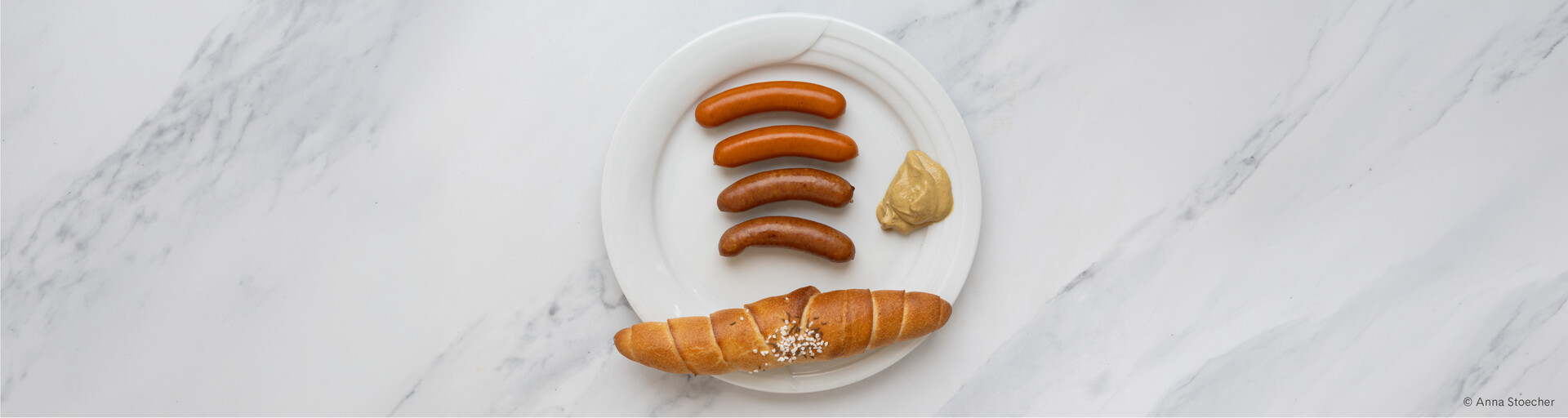 Verschiedene Wurstsorten auf Teller mit Senf und Salzstangerl | © Anna Stoecher