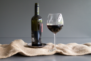 Ein Glas mit Rotwein neben einer Flasche | © Land schafft Leben