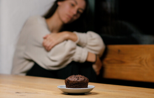 Essen und Psyche | © Land schafft Leben Frau sitzt traurig neben Muffin | © Land schafft Leben