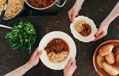 Essen und Psyche | © Land schafft Leben Gedeckter Tisch mit Händen die nach Gulasch greifen | © Land schafft Leben