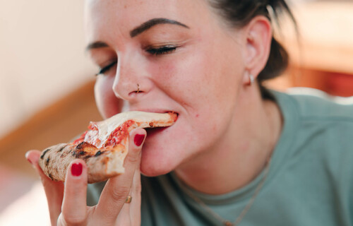 Essen und Psyche | © Land schafft Leben Frau beißt genüsslich in Pizzastück | © Land schafft Leben