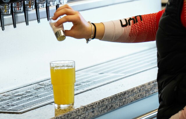 Person gibt Salz in ein Glas mit naturtrübem Apfelsaft | © Land schafft Leben