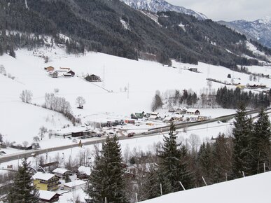 Häuser, Wald und Straße in verschneitem Tal | © Land schafft Leben