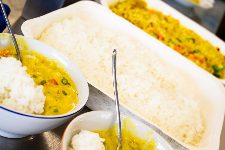 Reis in weißem Behältnis neben Schüsseln mit Reis und gelber Sauce | © Land schafft Leben