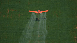 Rotes Flugzeug sprüht auf grünes Feld | © Greenpeace/Daniel Beltra
