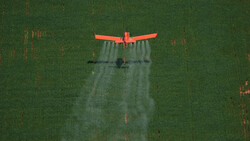Rotes Flugzeug sprüht auf grünes Feld | © Greenpeace/Daniel Beltra