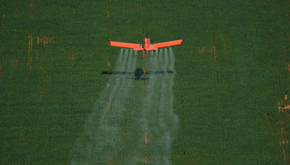 Rotes Flugzeug sprüht auf grünes Feld | © Greenpeace/Daniel Beltra