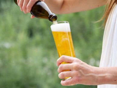 Blonde Frau schenkt Bier aus Flasche in glas | © Land schafft Leben