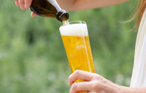 Blonde Frau schenkt Bier aus Flasche in glas | © Land schafft Leben