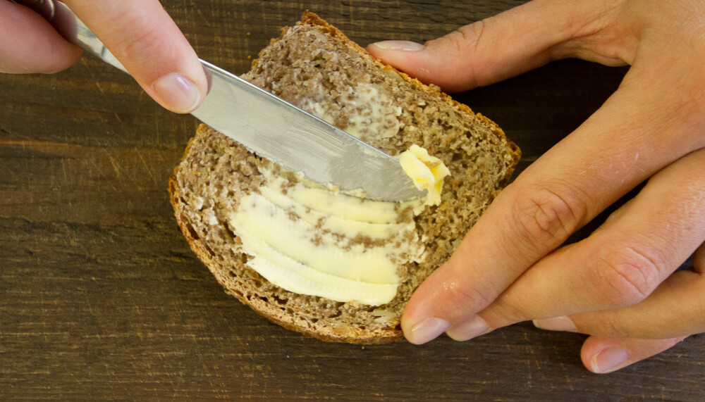 Person streicht Butter auf Schwarzbrot | © Land schafft Leben