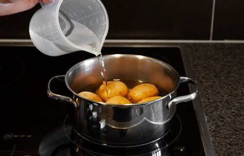 Person gießt Wasser in Topf mit Kartoffeln | © Land schafft Leben