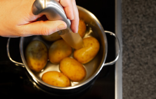Kartoffeln durch | © Land schafft Leben Person sticht mit Messer in Kartoffeln in Kochtopf | © Land schafft Leben