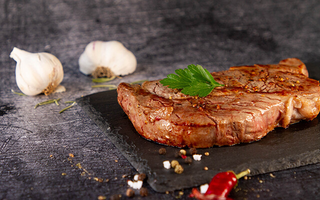 Rindersteak gebraten auf Teller mit Knoblauch und Petersilie | © Land schafft Leben