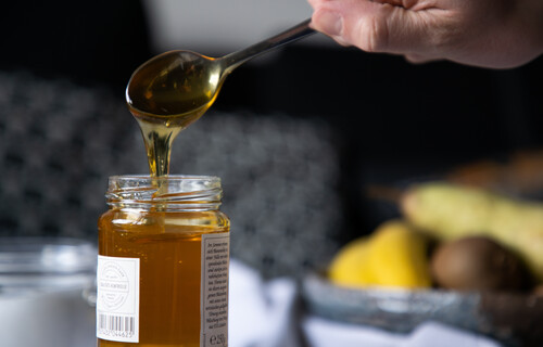 Honig rinnt von Löffel in Honigglas | © Land schafft Leben