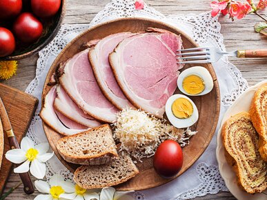 Osterschinken, Kren, Eier, Brot auf einem Teller, auf einem dekorierten Ostertisch mit Blumen, roten Ostereiern und Reindling | © Dusan Zidar/Shutterstock.com