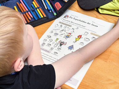 Kind mit Lehrmaterial "Die Superheldinnen und -helden der Jause" | © Land schafft Leben