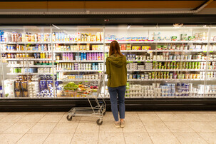 Frau steht vor Supermarktregal mit Milchprodukten | © Land schafft Leben
